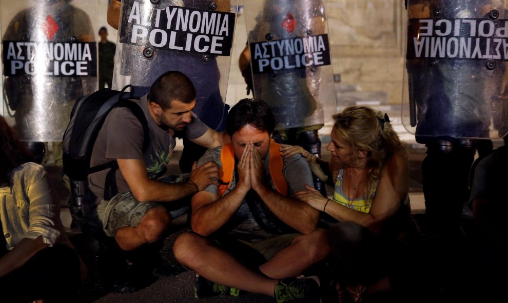 Yiorgos Avramidis, de 43 años, casado y con dos hijos de tres y seis años, es consolado por sus colegas frente a una línea policial en 2013. /  REUTERS - YANNIS BEHRAKIS
