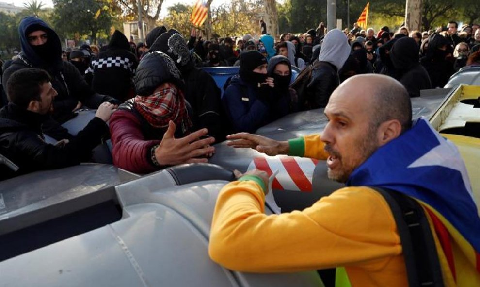 Un manifestante independentista trata de impedir que un grupo de encapuchados vuelquen contenedores en las inmediaciones de la Llotja de Mar de Barcelona/EFE