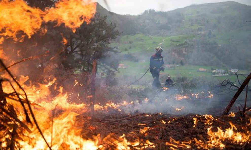 Un efectivo del Cuerpo de Bomberos del 112 de Cantabria durante las labores de extinción de un incendio forestal próximo a la localidad cántabra de Aes. El número de incendios activos en Cantabria ha bajado a 17 y los puntos más preocupantes están en Pena