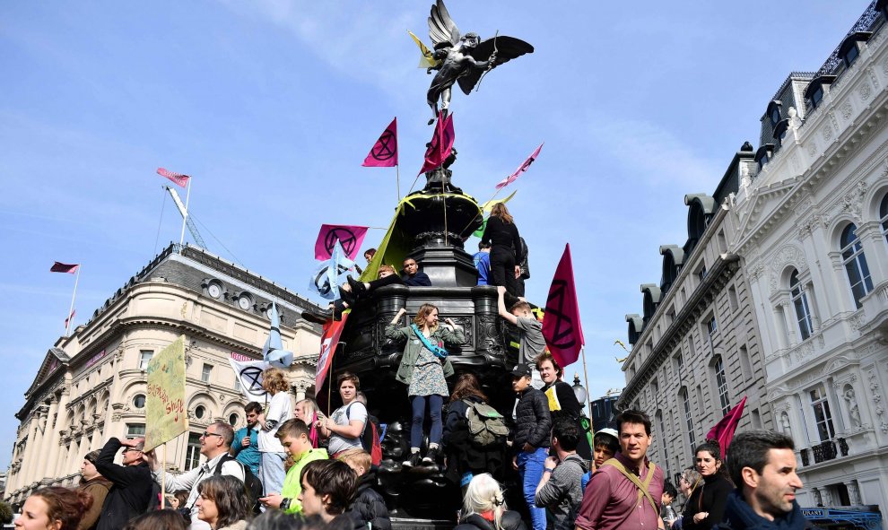 Los activistas del grupo de Extinción Rebelión ondean banderas mientras en la Fuente Conmemorativa de Shaftesbury durante una manifestación en Piccadilly Circus en Londres | AFP/ Daniel Leal-Oliva