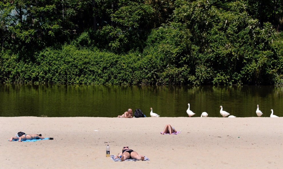 Un grupo de personas toma el sol en la playa de Las Moreras en Valladolid, ciudad en la que, al igual que en el resto de la Península, las temperaturas han subido hasta superiores a los 30 grados centígrados. | EFE