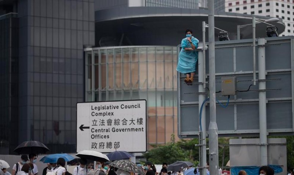 Un manifestante permanece encaramado sobre una señal de tráfico durante las protestas en contra de la polémica ley de extradición ante el Consejo Legislativo en Hong Kong, China. EFE / Jerome Favre