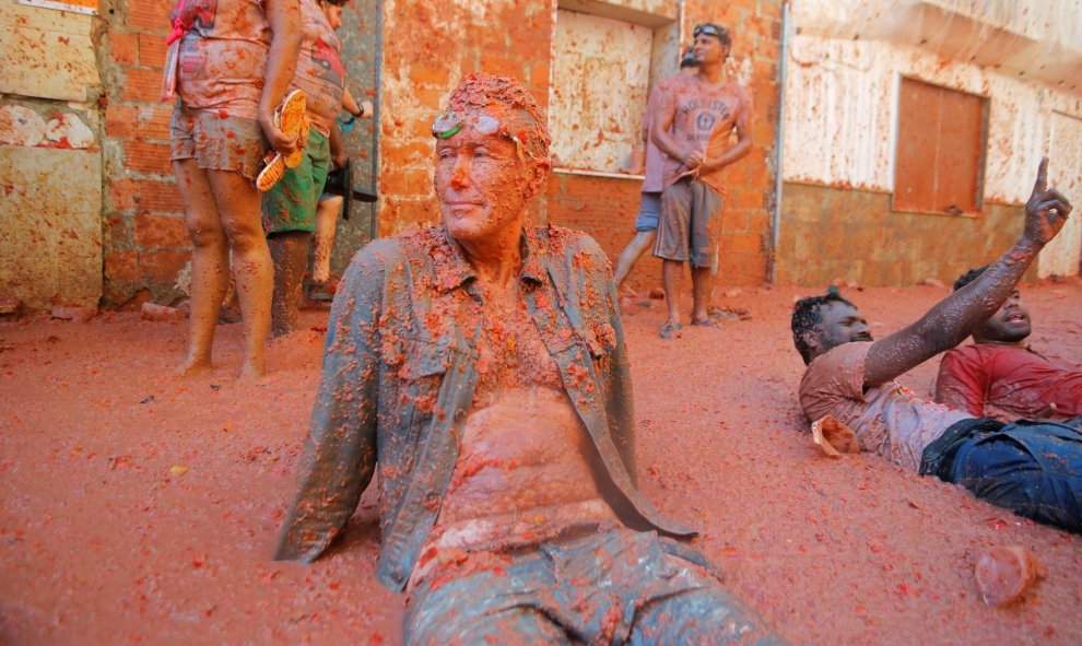 28/08/2019 - Un hombre se sienta en la acera tras la Tomatina celebrada en el pueblo Bunyol, donde un año más es el escenario de la batalla hortofrutícola más colorada del mundo. REUTERS/Heino Kali