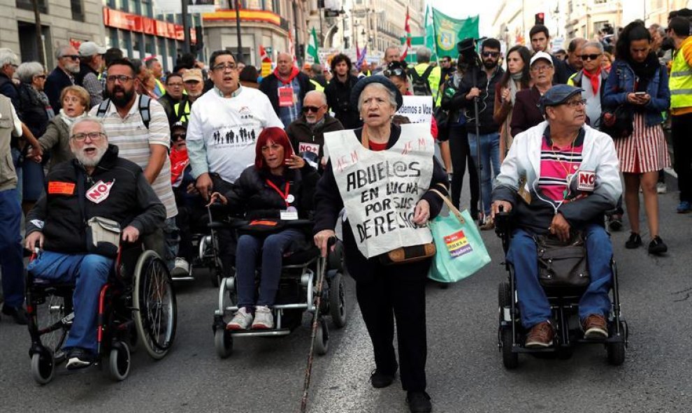 Un grupo de manifestantes encabezados por una mujer con un chaleco en el que se lee: "Abuel@s en lucha por sus derechos"./ Chema Moya (EFE)