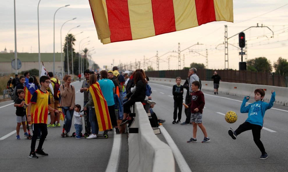 18/10/2019 - Unos niños juegan mientras los manifestantes marchan durante la huelga general de Cataluña en El Masnou./ REUTERS (Albert Gea)