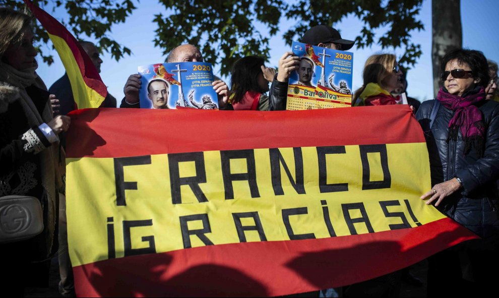 Varios franquistas sostienen una bandera de España con un texto pintado sobre ella que pone "Franco Gracias" en los alrededores del cementerio de Mingorrubio-El Pardo. / Jairo Vargas