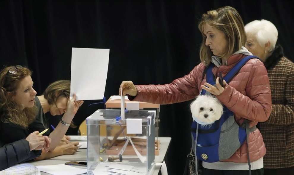 Una mujer vota acompañada de su mascota en un local electoral de Barcelona. EFE/ Andreu Dalmau