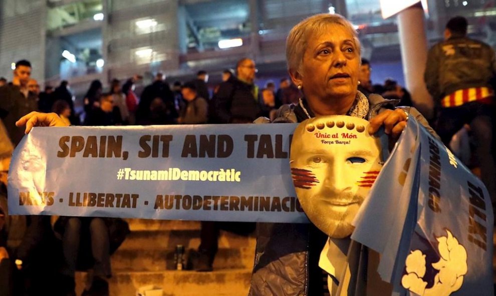 18/12/2019.- Una mujer con una careta de Messi y un cartel de Tsunami Democràtic. / EFE- TONI ALBIR