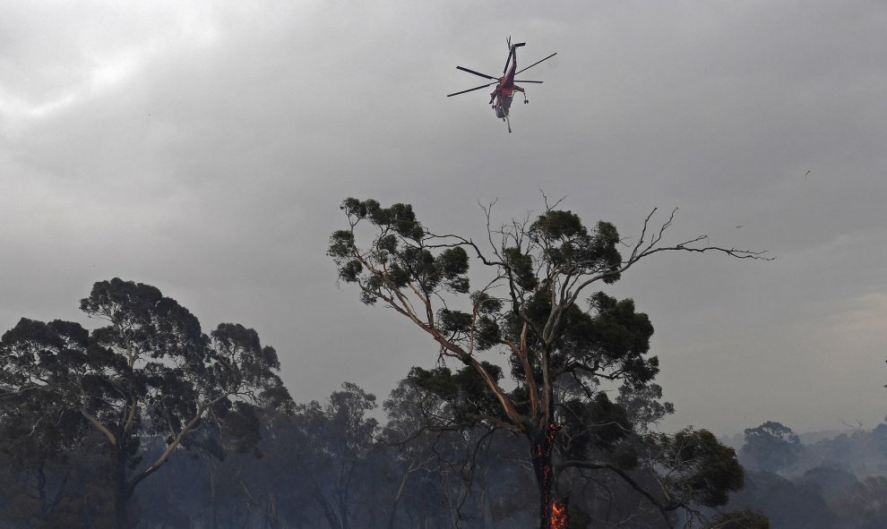 Un helicóptero sobrevuela un área devastada por los incendios en Australia. REUTERS