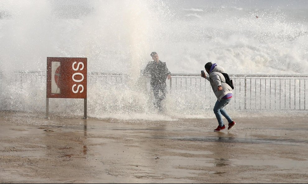 20/01/20- Turistas toman fotos mientras las olas del mar los cubren durante el temporal Gloria en la playa de la Barceloneta, en Barcelona. REUTERS / Nacho Doce