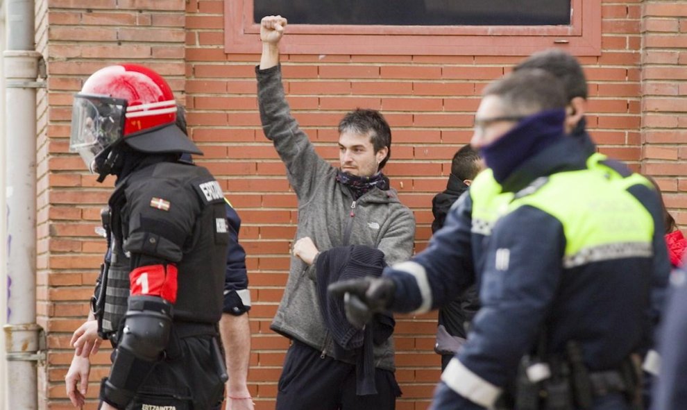 Un hombre alza el puño mientras es identificado por agentes de la Ertzaintza y la Policía Local en el centro de Vitoria | EFE
