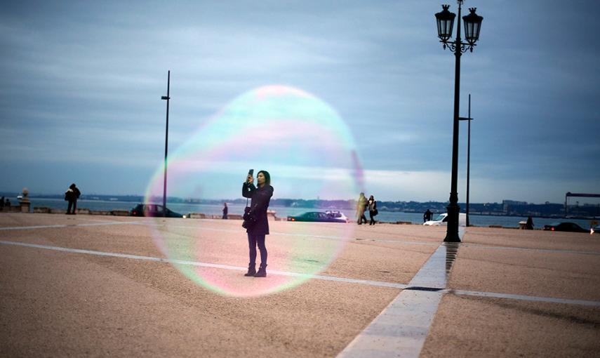 Un turista, a través de una burbuja de jabón mientras se toma una foto en la plaza de Comercio, en el centro de Lisboa. // RAFAEL MARCHANTE (REUTERS)