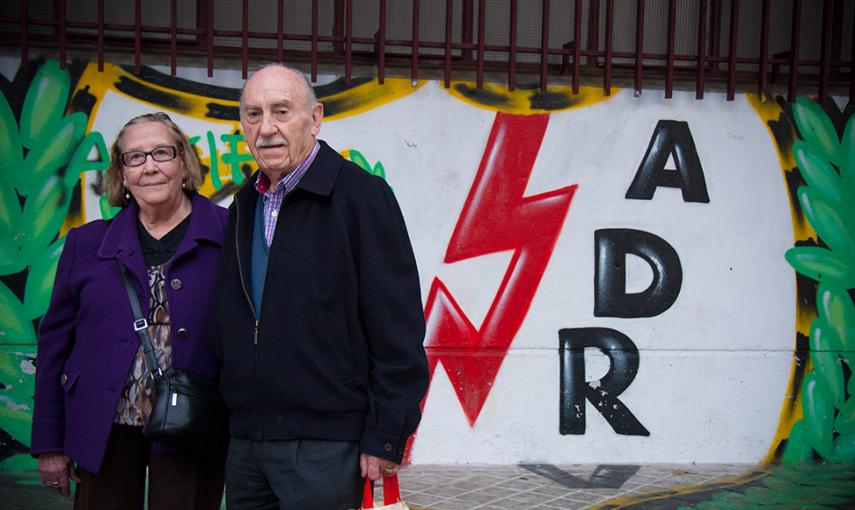 Natividad y Eladio, dos vecinos de Vallecas y afionados del club, posan ante una pintada con el escudo del club. // CHRISTIAN GONZÁLEZ