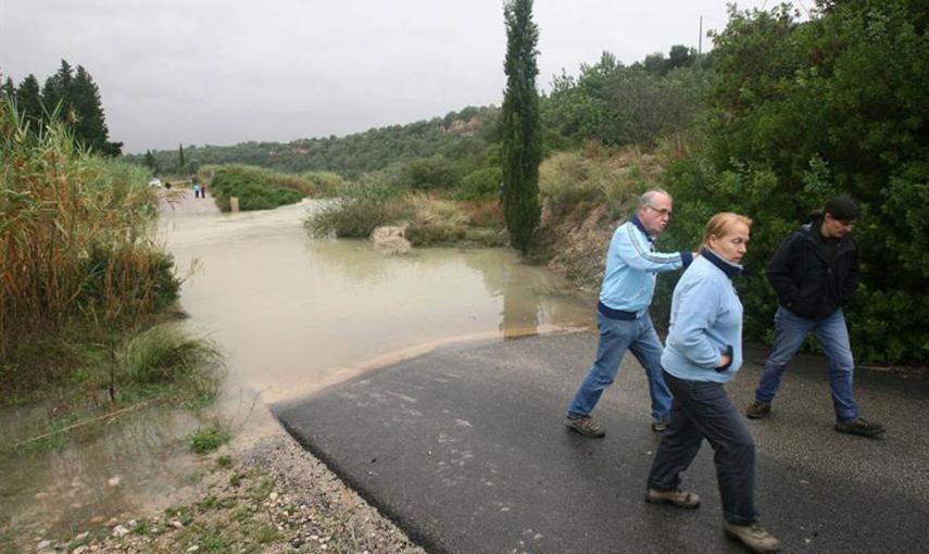 Varias personas junto a una carretera cortada en Tortosa a causa del temporal que desde ayer azota Cataluña que ha obligado a cortar al tráfico numerosas carreteras. // EFE