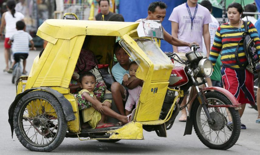 Una familia filipina se dirige en su triciclo a un centro de evacuación en Manila. // EFE/EPA/DENNIS M. SABANGAN