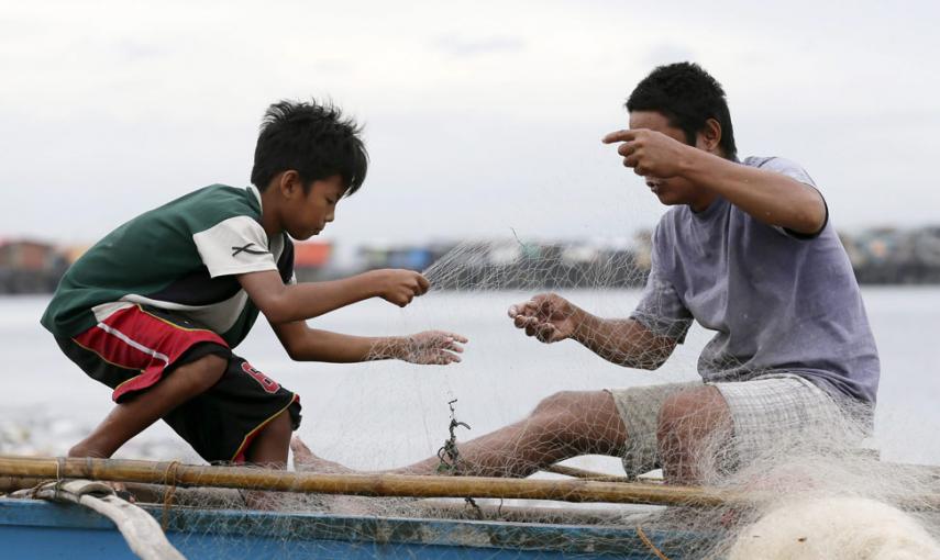Un padre y su hijo aseguran su barca de pesca para prevernir la llegada del tifón Hagupit. // EFE/EPA/DENNIS M. SABANGAN