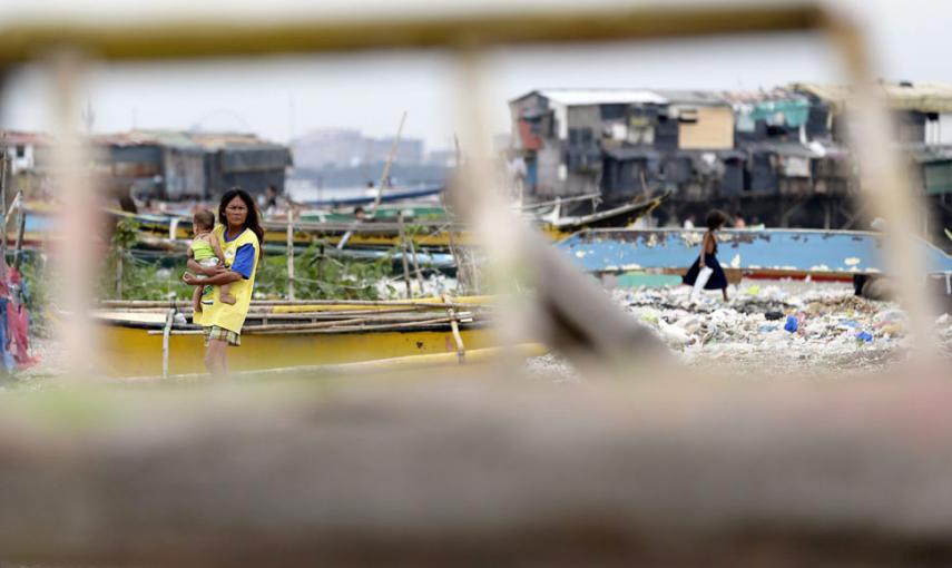 Una madre y su hijo caminan junto a varias barcas de pesca castigadas por el paso del tifón Hagupit. // EFE/EPA/DENNIS M. SABANGAN