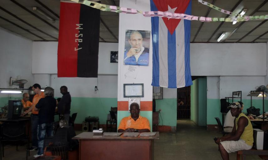 Varios hombres esperan dentro de un taller de reparaciones de televisores en La Habana. EFE/Ernesto Mastrascusa