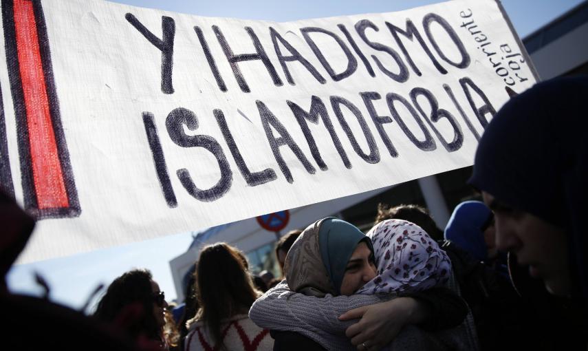 Two women embrace under a banner that reads, "Not Islamophobia and jihadism" during a rally by members of the Muslim community of Madrid outside Madrid's Atocha train station, January 11, 2015, in solidarity with the victims of a shooting by gunmen at the