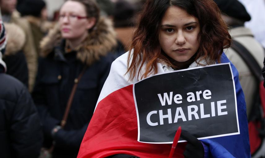 A woman wearing a French national flag holds a 'We are Charlie' sign during a march for the victims of the shootings by gunmen at the offices of the satirical weekly newspaper Charlie Hebdo in Paris, in Liverpool, northern England January 11, 2015. REUTER