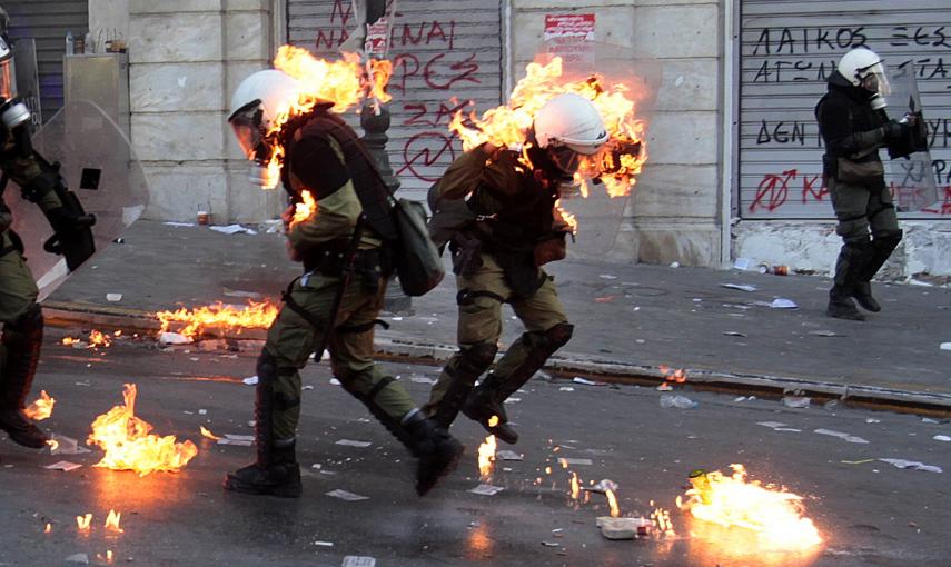 El fuego de unos cócteles molotov alcanza a unos agentes de policía en unos enfrentamientos con manifestantes cerca de la sede del Parlamento en la Plaza Syntagma de Atenas (20 de octubre 2011). REUTERS / Yannis Behrakis