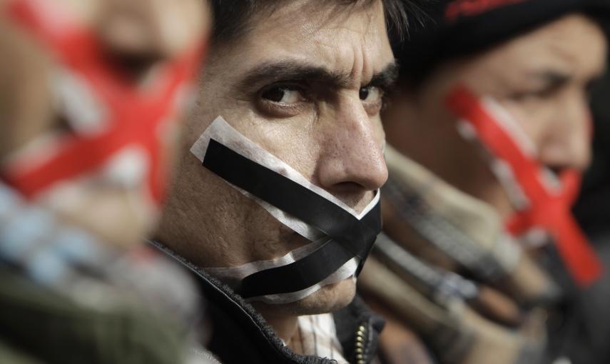 Inmigrantes y solicitantes de asilo, con la boca cubierta con cinta adhesiva, en una manifestación en el centro de Atenas (1 de febrero 2011). REUTERS / John Kolesidis
