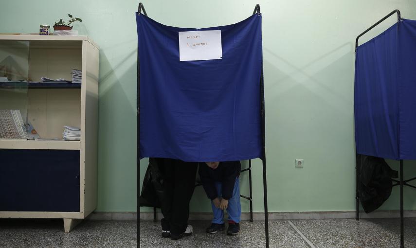 Un padre con su hijo dentro de una cabina de votación en Atenas. REUTERS/Yannis Behrakis