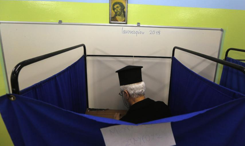 Un sacerdote ortodoxo griego dentro de una cabina electoral. REUTERS/Yannis Behrakis