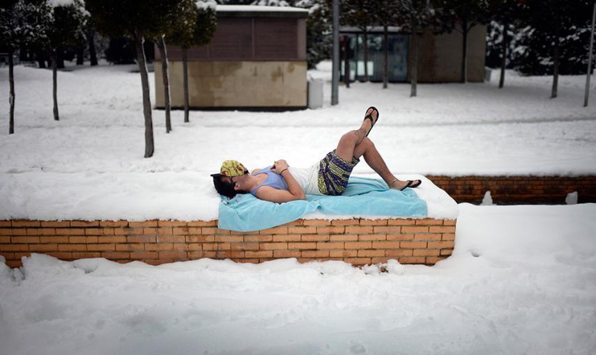 Un joven sobre una toalla de playa, en un parque cubierto de nieve en Vitoria. /VICENTE WEST (REUTERS)