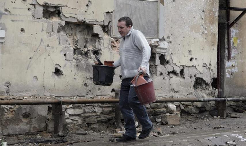 Un hombre camina delante de una pared de su vivienda que ha sufrido daños tras un bombardeo en Donetsk, Ucrania, hoy, lunes 9 de febrero de 2015. El Gobierno alemán anunció ayer la celebración de una cumbre en Minsk (Bielorrusia) este miércoles con partic