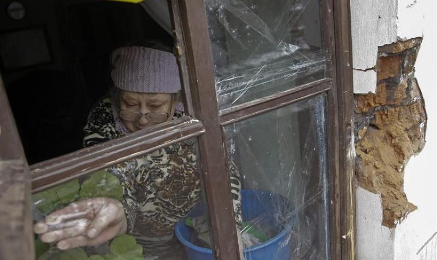 Una mujer repara con cinta adhesiva una ventana que quedó destrozada tras un bombardeo en Donetsk, Ucrania, hoy, lunes 9 de febrero de 2015. El Gobierno alemán anunció ayer la celebración de una cumbre en Minsk (Bielorrusia) este miércoles con participaci