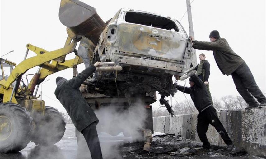 Varios operarios retiran un coche dañado tras un bombardeo en el puente Petrovskiy de Donetsk, Ucrania, el 10 de febrero del 2015. Unidades de las Guardia Nacional apoyadas por efectivos del Ejército ucraniano se han hecho con el control de varias ciudade