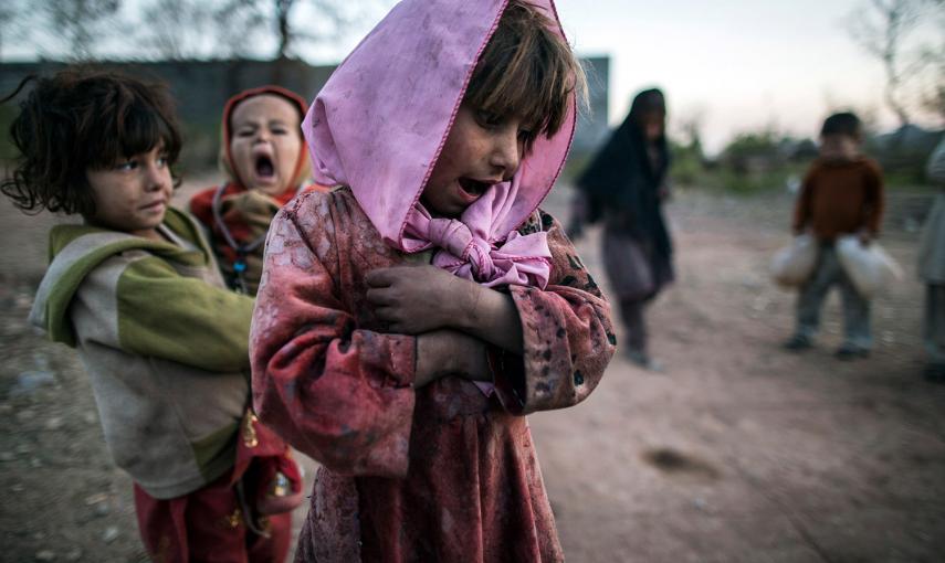 Una niña mira a sus amigos, mientras juegan a la rayuela a las afueras de Islamabad (Pakistán). /ZOHRA BENSEMRA (REUTERS)
