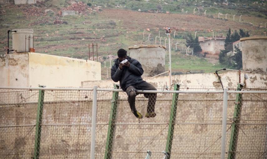 Un immigrante africano come un sándwich lanzado por agentes de la Guardia Civil, mientras permanece sentado en lo alto de la valla de Melilla. /JESÚS BLASCO DE AVELLANEDA (REUTERS)