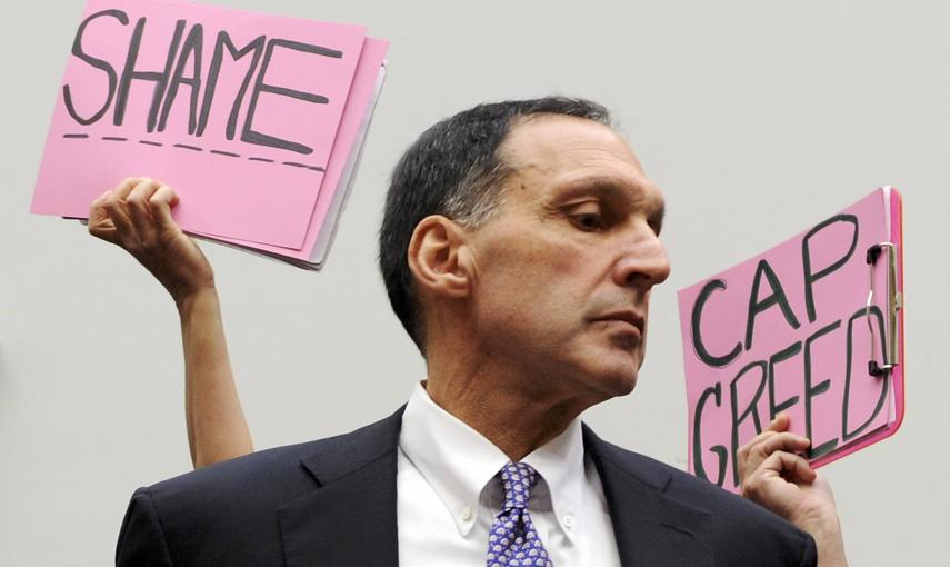 Algunos manifestantes sostienen pancartas detrás del presidente ejecutivo de Lehman Brothers, Richard Fuld, antes de iniciar su comparecencia en el Congreso de EEUU para explicar la quiebra de la entidad, y en la que aseguró que las autoridades estadounid