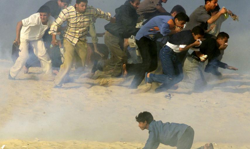 Los palestinos tratan de huir de los soldados israelíes que han disparado gas lacrimógeno, durante unos enfrentamientos en la Franja de Gaza (20 de octubre 2000). REUTERS / Reinhard Krause