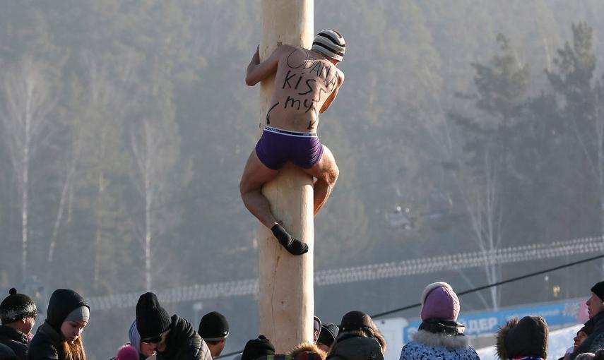Un hombre sube por un palo de madera hasta una altura de 13 metros para conseguir un premio, durante las celebraciones Maslenitsa en la estación de esquí Bobrovy Log, en Krasnoyarsk (Rusia)
