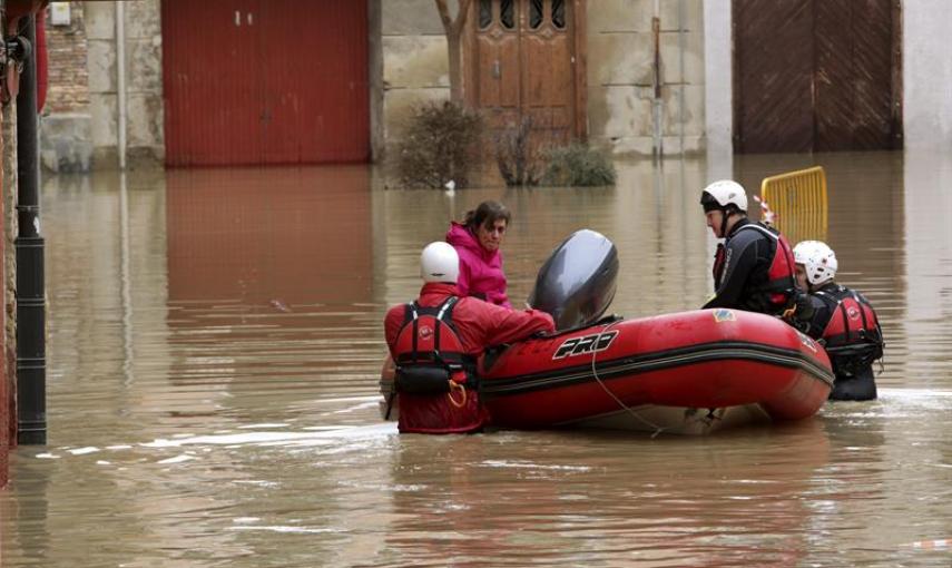 Voluntarios de Cruz Roja acompañan a una mujer hasta su casa por las calles anegadas del casco histórico de Tudela (Navarra), dentro de la atención que prestan a los vecinos que han quedado incomunicados por la crecida del río Ebro, desbordado a causa de