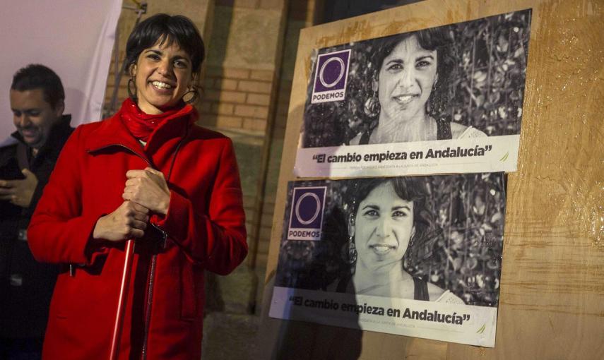 La candidata a la Presidencia de la Junta por Podemos, Teresa Rodríguez, ayuda a pegar los carteles electorales durante el acto de inicio de la campaña electoral andaluza celebrado anoche en la plaza Fragela, en Cádiz./ EFE