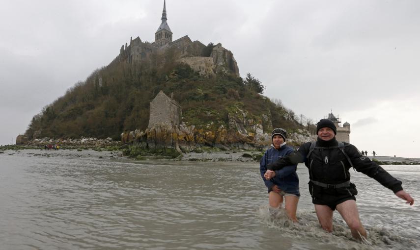 La gente camina por las aguas desde la abadía del Siglo XI del Mont Saint-Michel, en Normandía. REUTERS / Pascal Rossignol
