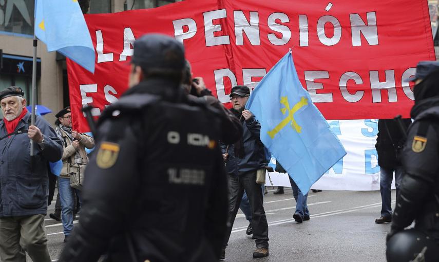 Participantes en las Marchas por la Dignidad pasan ante varios policiales en la Plaza de Colón, donde han confluido las nueve columnas procedentes de todas las comunidades autónomas. EFE/Ballesteros