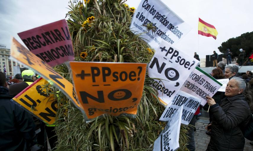 Una mujer coloca unas pancartas en un arbusto durante las Marchas de la Dignidad. REUTERS / Sergio Pérez