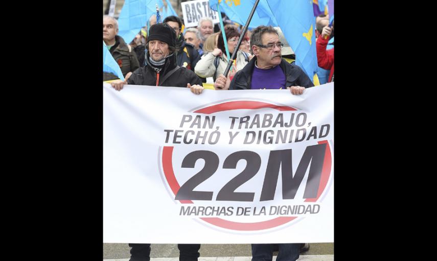 Dos participantes en las Marchas por la Dignidad tras una de las pancartas en la Plaza de Colón. EFE/Ballesteros