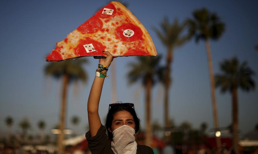 La pizza, alimento de los festivales en el Coachella. Una mujer posa con una réplica gigante.