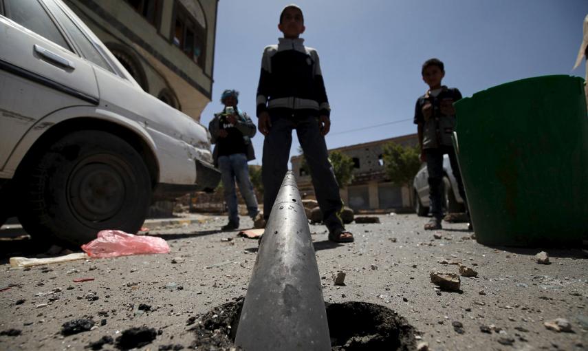 Un niño, ante un proyectil de artillería parcialmente enterrado en Sanaa. /MOHAMED AL-SAYAGHI (REUTERS)