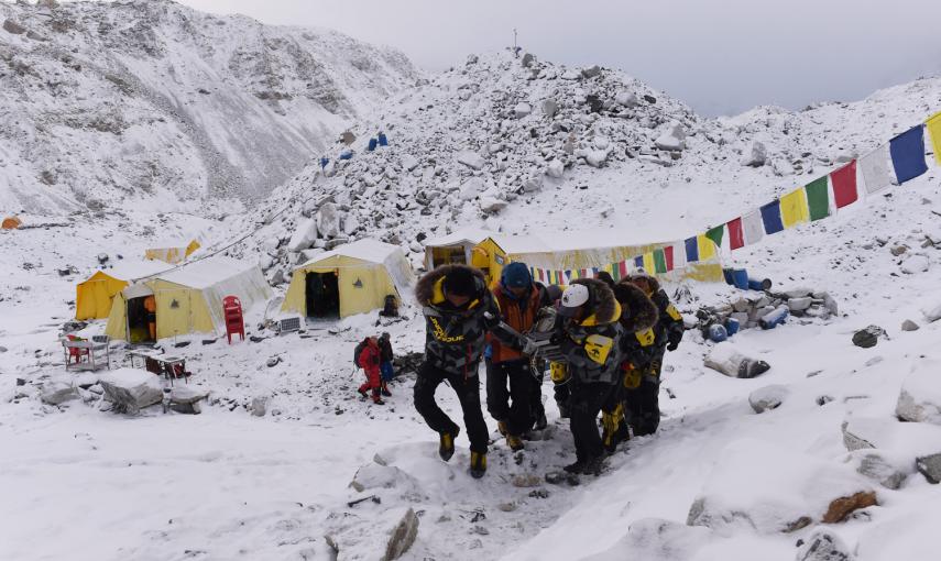 Una persona herida es llevada por los miembros de rescate para ser transportada en helicóptero desde el campamento base del Everest este domingo.Los cuerpos de los fallecidos se encuentran en tiendas de campaña de color naranja. -AFP PHOTO / ROBERTO SCHMI