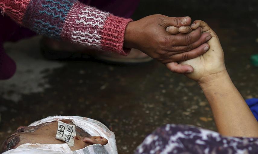 Una mujer sostiene la mano de un familiar fallecido durante el terremoto, fuera de un hospital en Katmandú, Nepal.- REUTERS / Adnan Abidi