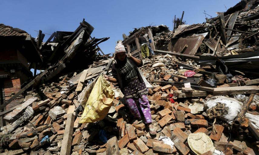 Una mujer porta sus pertenencias mientras camina sobre los escombros de una vivienda en Bhaktapur, Nepal./ REUTERS/Adnan Abidi