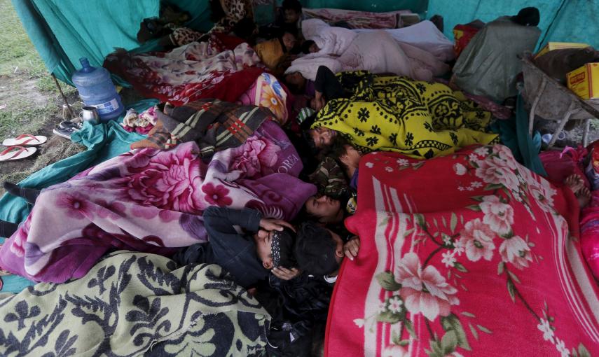 Una víctima del terremoto lleva en brazos a su hermana fuera de su refugio improvisado en las afueras de Katmandú, Nepal./ REUTERS/Adnan Abidi