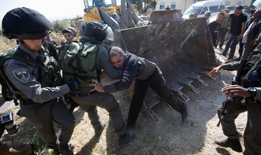 Policías israelíes forcejean con un hombre que intenta impedir el avance de un Bulldozer el el pueblo de Soba, cerca de la ciudad cisjordana de Hebrón.- MUSSA QAWASMA (REUTERS)